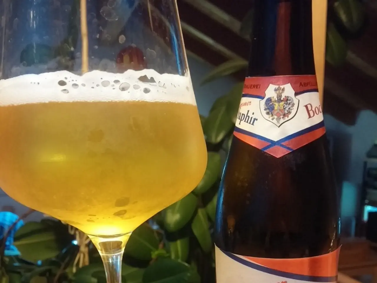 In this image there is a wine bottle and also a glass of wine placed on the wooden surface. In the...