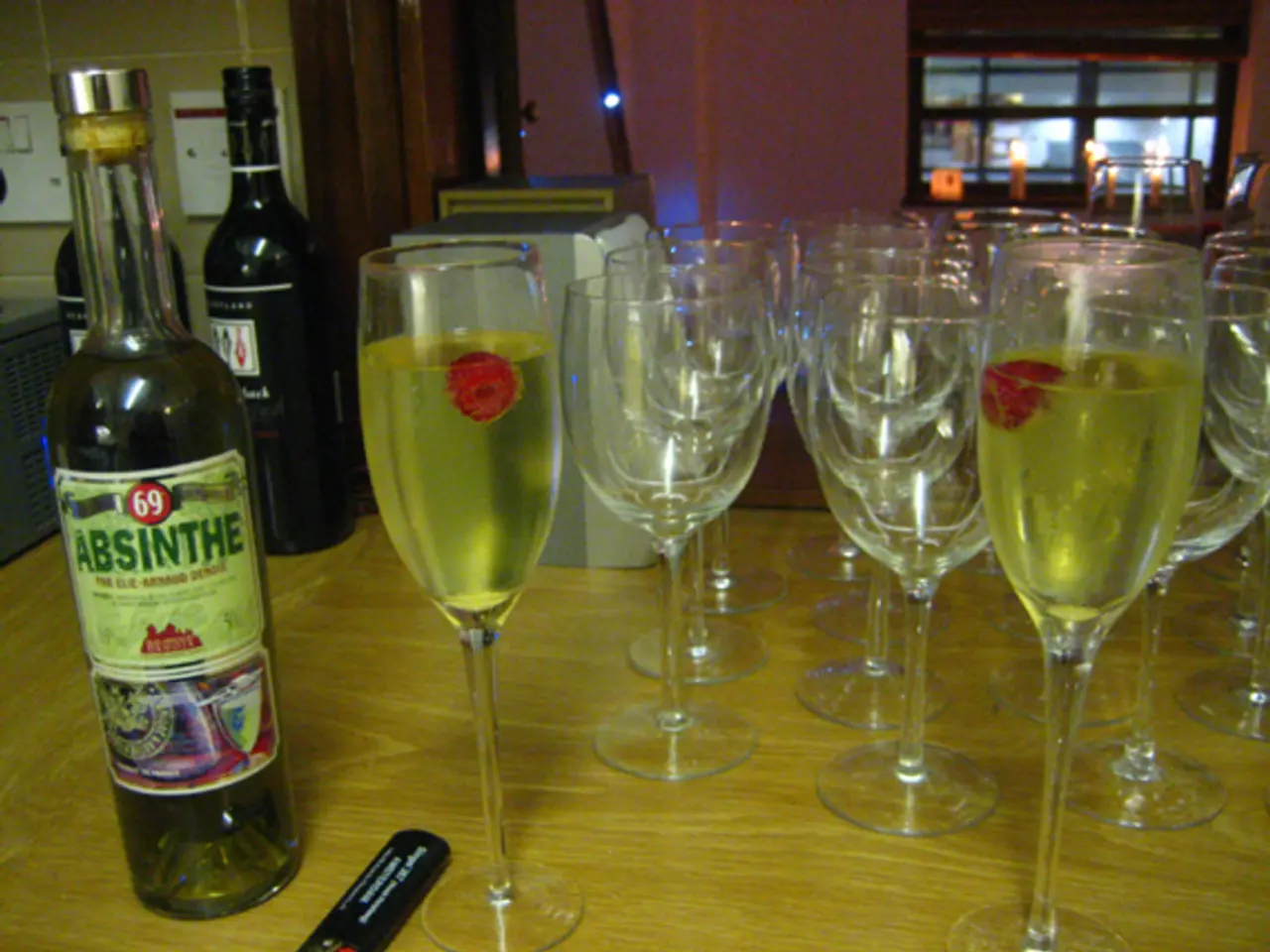 There are three wine bottles and some wine glasses on a table.