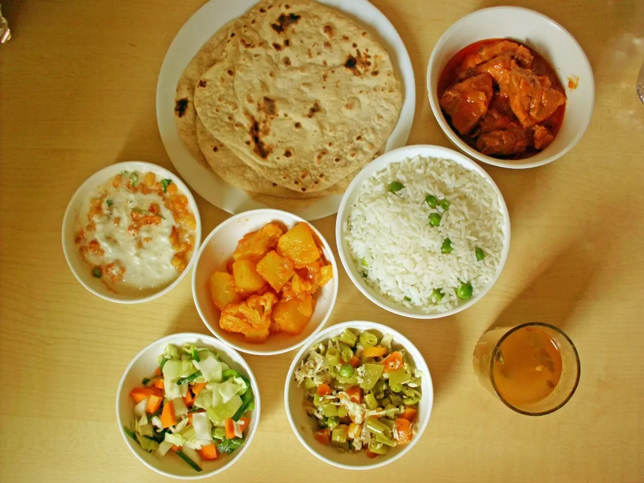In the foreground I can see a plate in which chapatis are there and bowls in which curries, salad,...