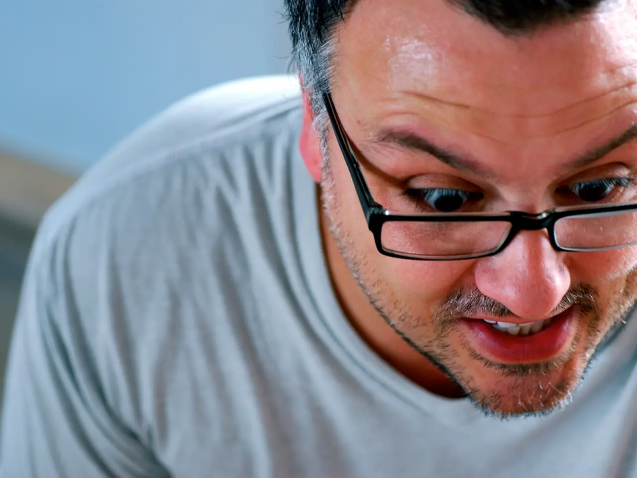 In the image there is a man in grey t-shirt and specs in the front.