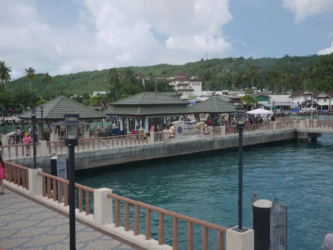 In this image there is a big river and bridge on the top where so many people are standing under...