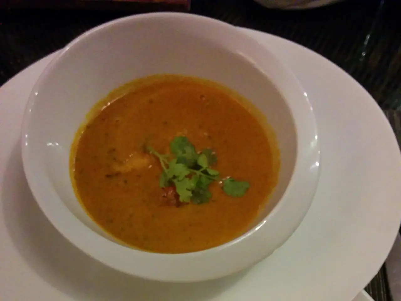 The image shows a white plate topped with a bowl of curry and rice, accompanied by a plate of naan...