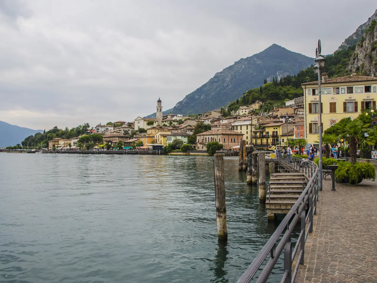 The image shows a picturesque view of a small town on the shore of Lake Como, Italy. We can see the...