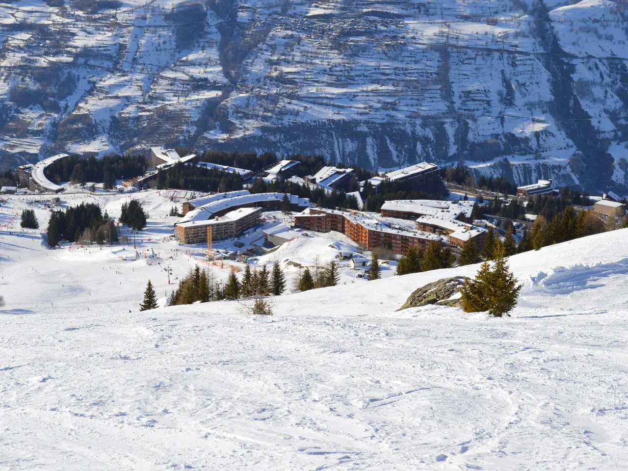 The image shows a picturesque view of a ski resort nestled in the mountains, with snow-covered...