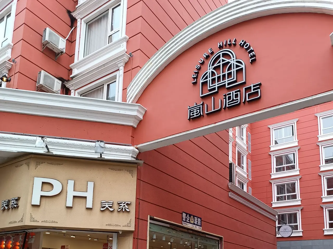 The image shows a group of people walking down a street in front of a building with windows, air...