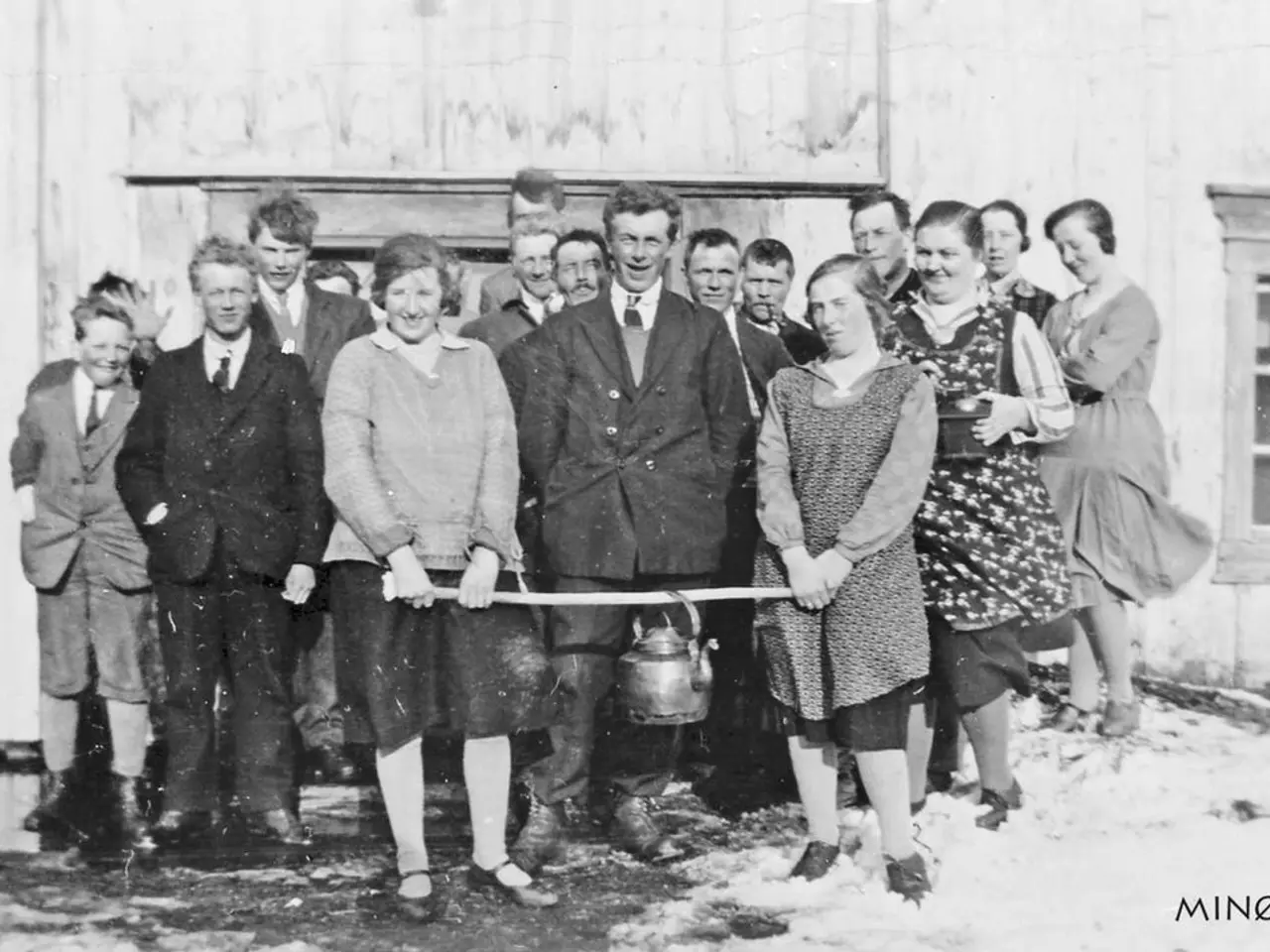 The image shows a group of people standing next to each other in front of a building, smiling and...