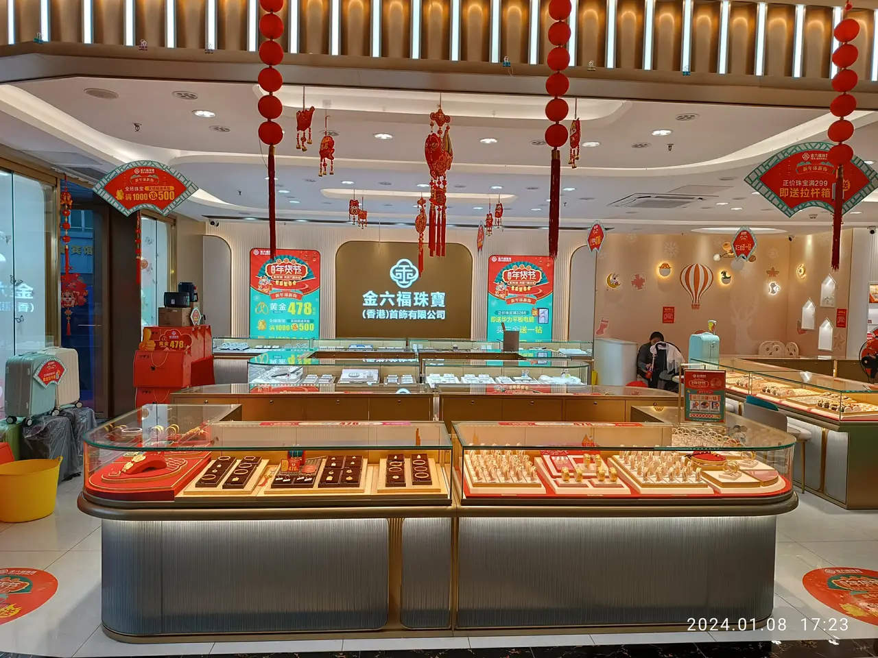 The image shows a store filled with lots of different types of chocolates on display, with a person...