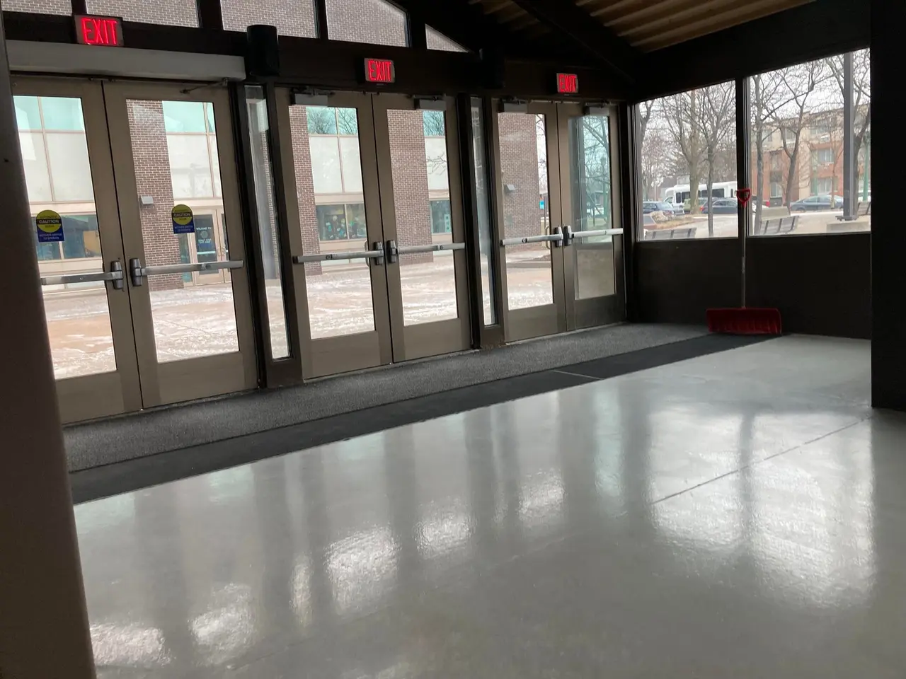 The image shows a large room with a lot of windows and doors, a broomstick on the floor, sign...