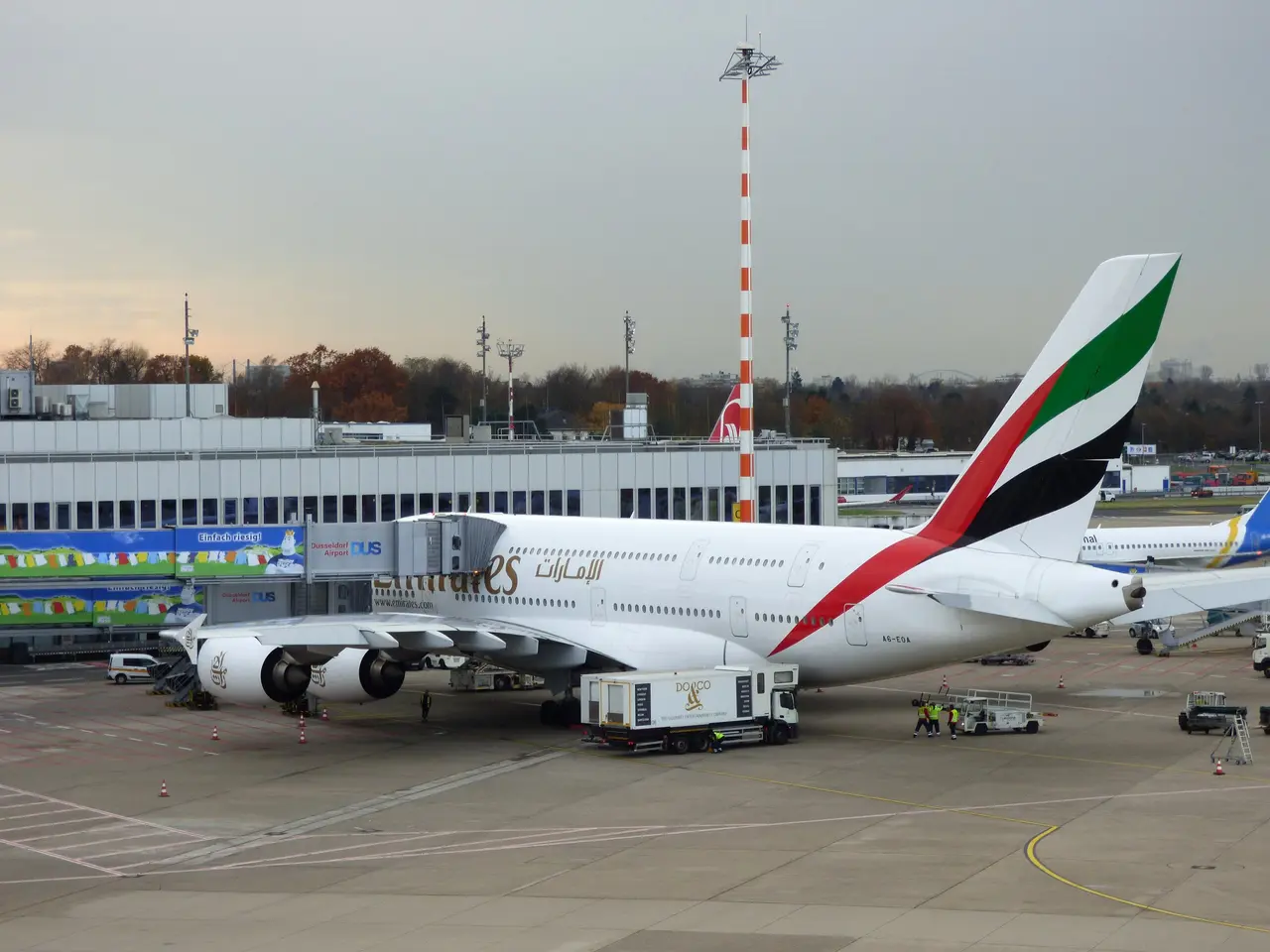 The image shows an Emirates Airbus A380-800 at Frankfurt Airport, surrounded by vehicles and...