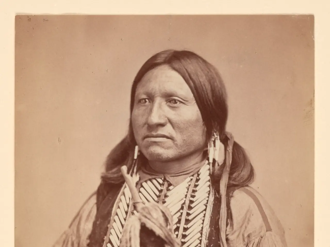 The image shows an old black and white photo of an Indian man wearing traditional clothing and...