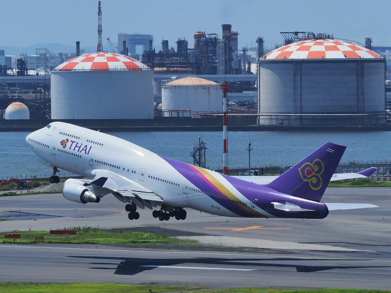 The image shows a Thai Airways Boeing 747-400 taking off from an airport runway, surrounded by...