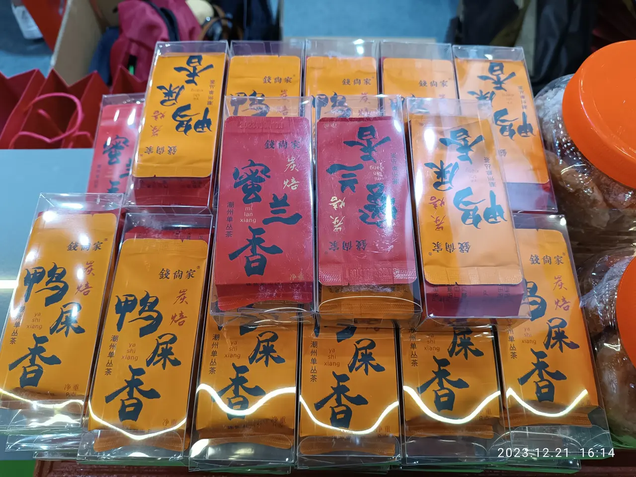 The image shows a table topped with lots of different types of food, including packets with text on...