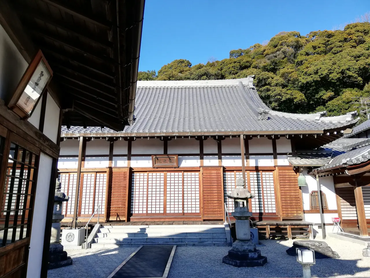 The image shows a traditional Japanese building with a lot of windows and a door, surrounded by...
