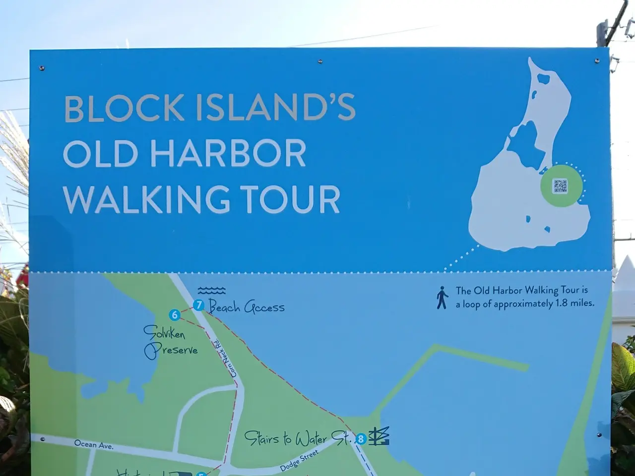 The image shows a board with a map of Block Island's Old Harbor Walking Tour, surrounded by lush...