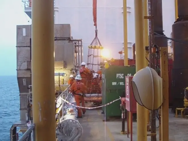 This is a ship. In this there are poles, boxes, railings. And there are some people wearing...