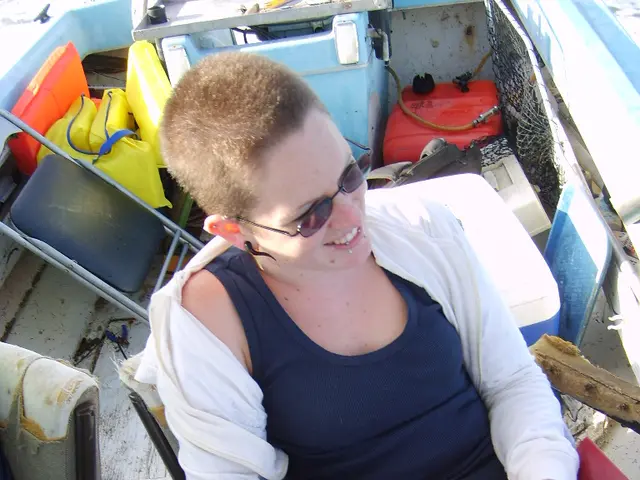 There is a lady wearing goggles is holding a belt and a bottle is sitting on a chair. Near to her...