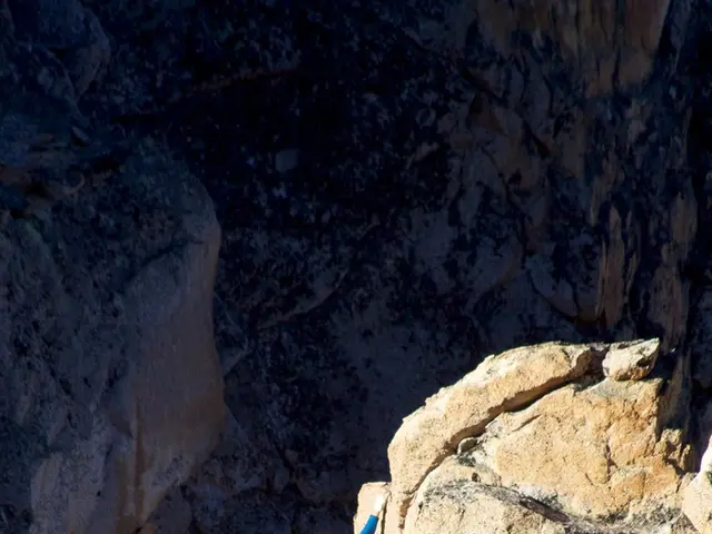 In this image I can see a person climbing a mountain.