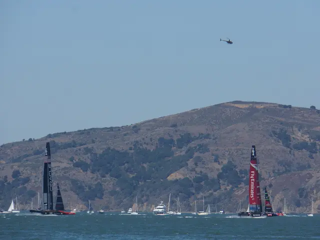 In the image I can see a beach in which there are some boats, ships and also I can see a mountain,...