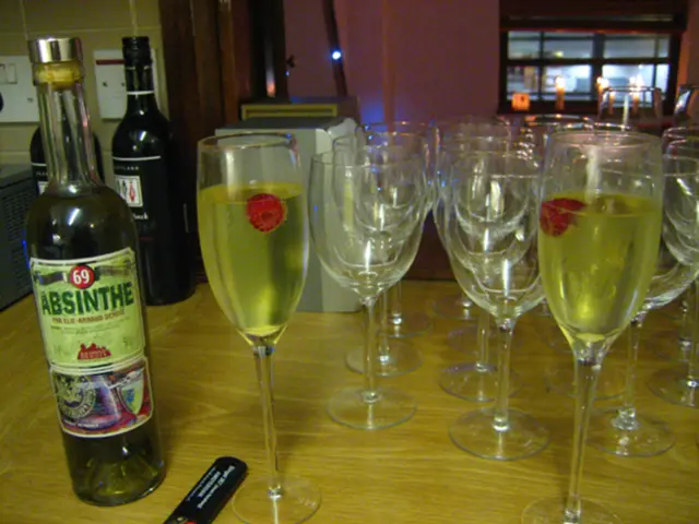 There are three wine bottles and some wine glasses on a table.