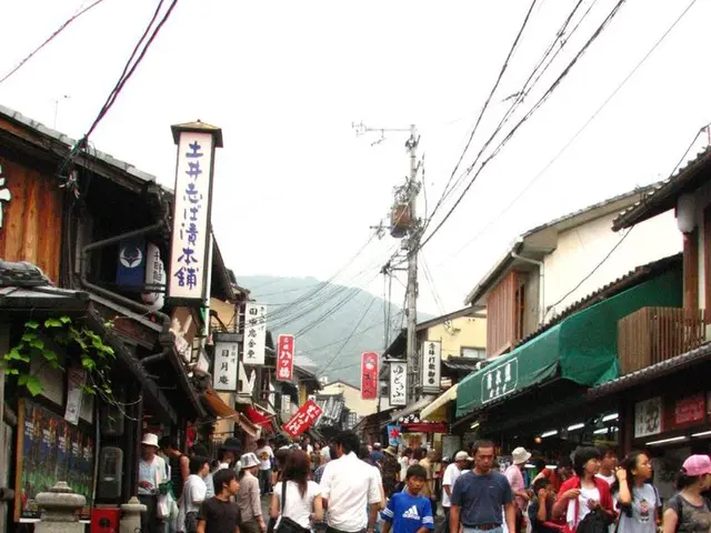 This picture describes about group of people, few are standing and few are walking on the road,...