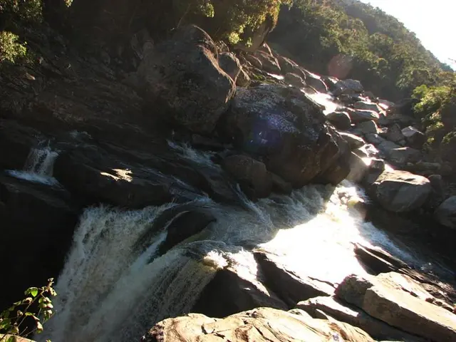 In this picture we can see the waterfalls, rocks, trees and the sky.