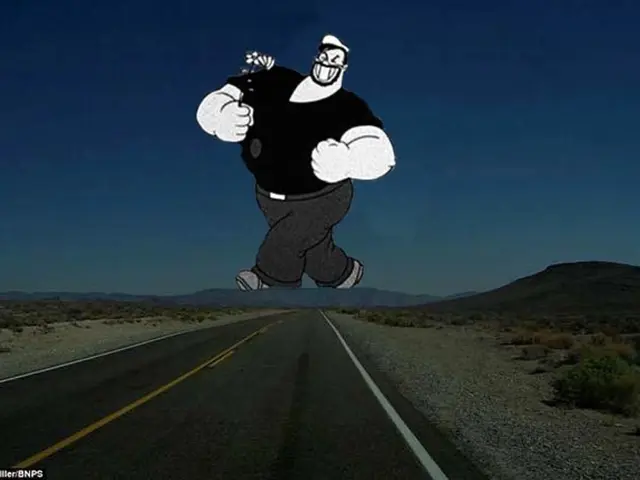 In this image there is a road. In the background of the image there is a mountain, cartoon and sky.