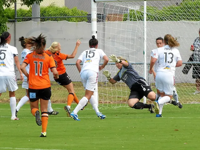 In the image a group of women are playing some game in the ground and behind them there is a mesh,...