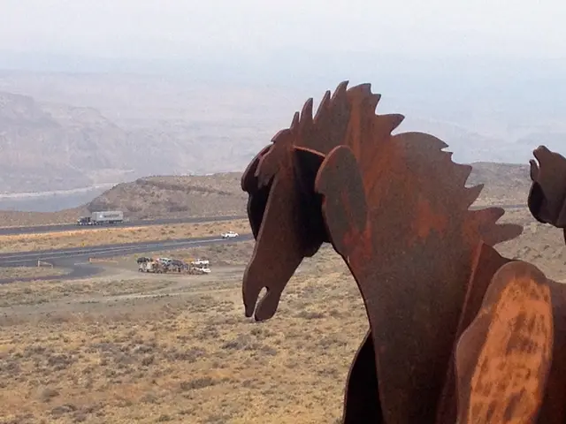 As we can see in the image there are hills, vehicles, road, group of people and horse statues and...