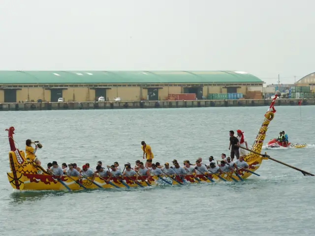 The image shows a group of people in a dragon boat on the water, rowing with paddles. In the...