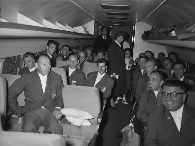 The image shows a black and white photo of a group of people sitting in an airplane. There are men...