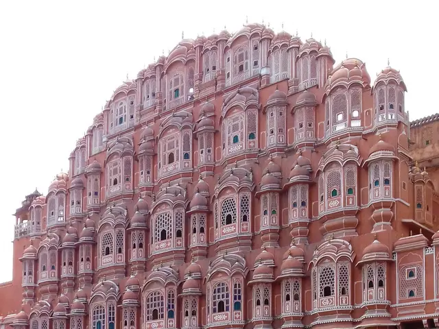 The image shows the Hawa Mahal in Jaipur, Rajasthan, India. It is a large building with many...