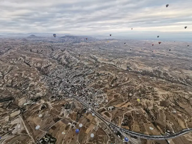The image shows a stunning view of Cappadocia, Turkey, with hot air balloons flying over the valley...