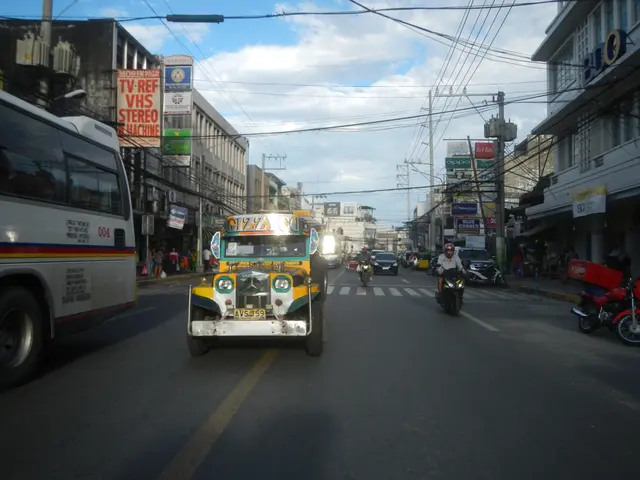 The image shows a city street filled with lots of traffic, including a bus and a jeepney. There are...