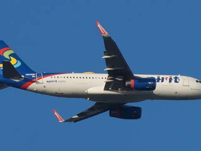 The image shows a Spirit Airlines Airbus A320-200 in flight, with its white, blue, red and yellow...