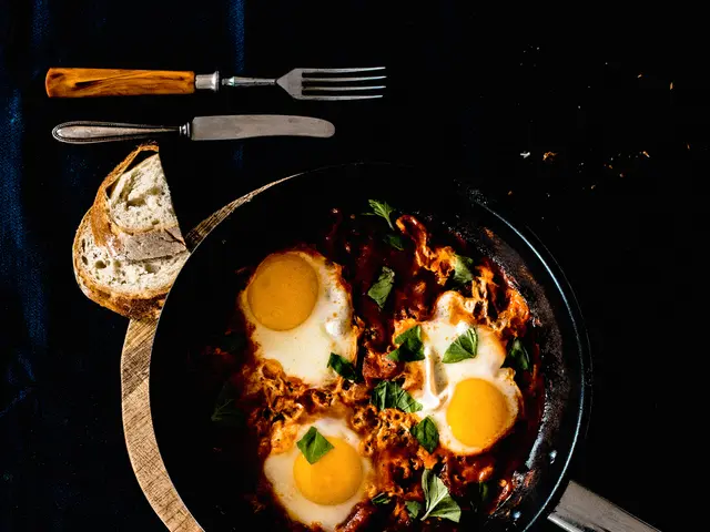 The image shows a pan filled with shakshuka, a traditional Middle Eastern dish, on top of a wooden...