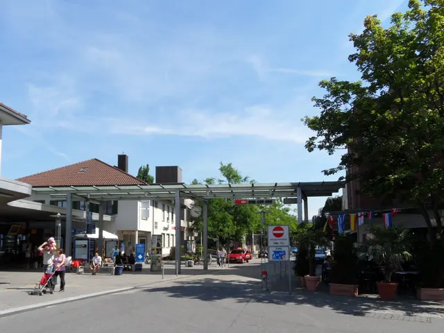 The image shows a city street with people walking down it, some of them holding strollers. There...