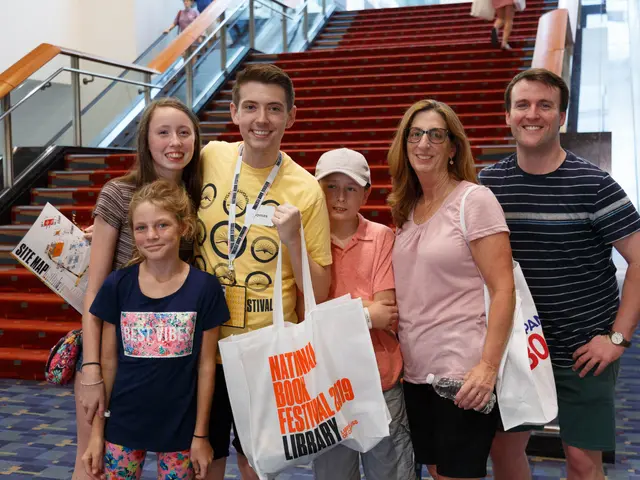 The image shows a group of people standing next to each other in front of an escalator, smiling and...