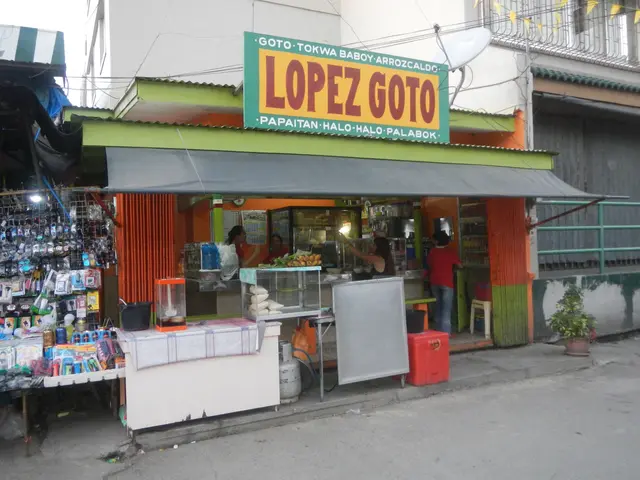 The image shows a food stand called Lopez Goto in Manila, Philippines. There are a few people...
