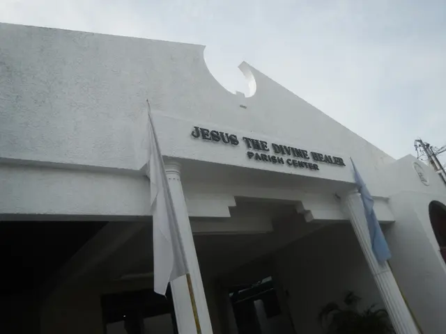 The image shows Jesus the Divine Healer Parish Center, a building with text on the wall, pillars,...
