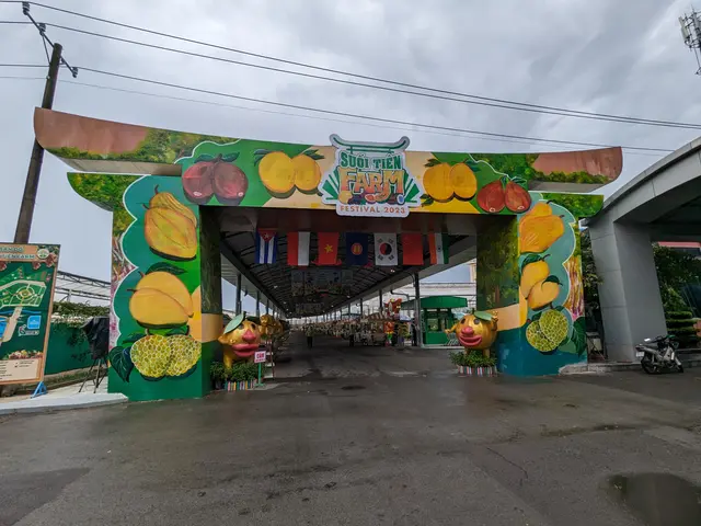 The image shows the entrance to a fruit farm in Thailand, with an arch adorned with paintings of...