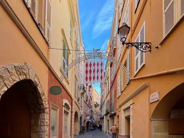 The image shows a narrow street in the old town of Palma de Mallorca, Spain. On either side of the...