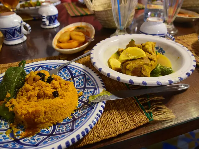 The image shows a table topped with plates of food and glasses of wine, as well as bowls, jars,...
