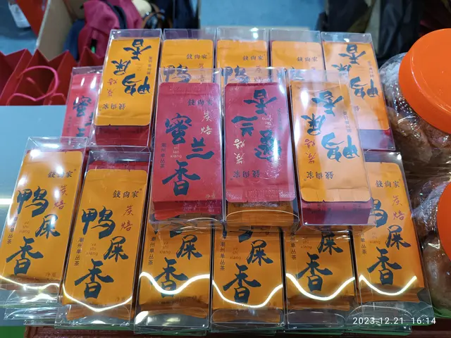 The image shows a table topped with lots of different types of food, including packets with text on...