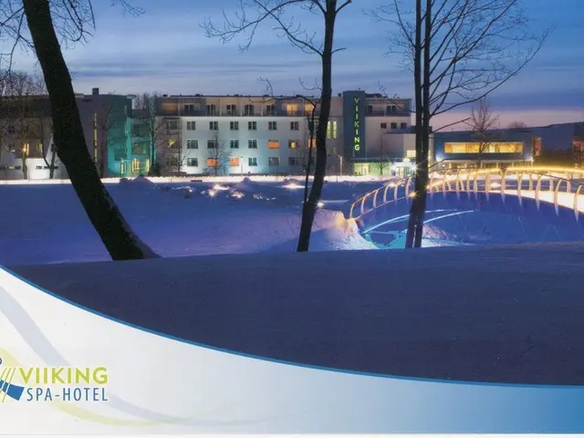 The image shows a winter scene of a Viking Spa Hotel, with snow on the ground, a bridge with...