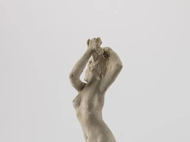 The image shows a sculpture of a nude woman with her hands on her head, created by Louis Cowkins in...