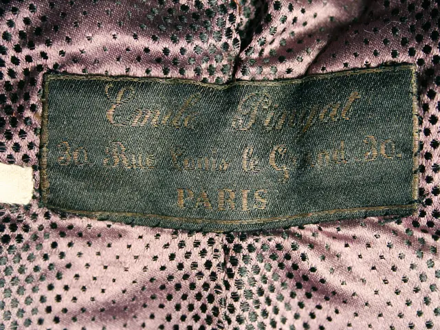 The image shows a close up of a pink dress with a black label on it. The label has text written on...