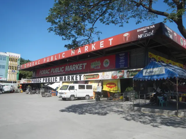 The image shows a public market with a van parked in front of it, surrounded by buildings, stores,...