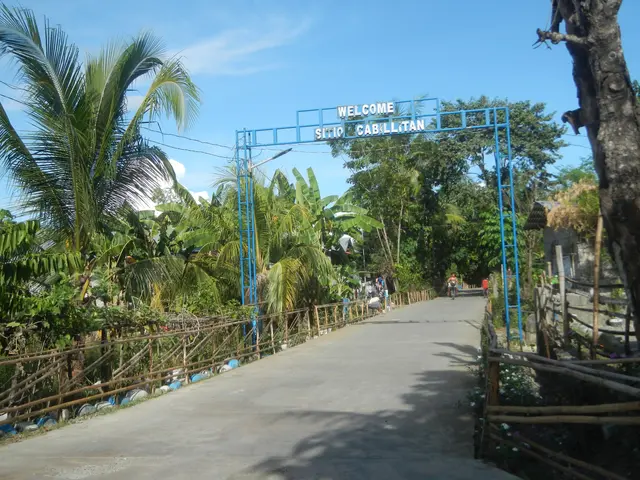 The image shows the entrance to a resort in the Philippines, with an arch with text on it, a wooden...